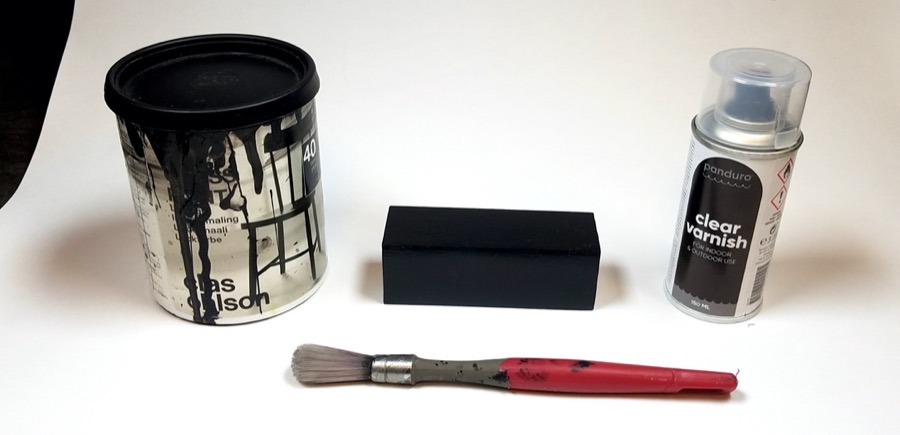 The painted resonator together with the paint, varnish, and paint brush inplicated in the process